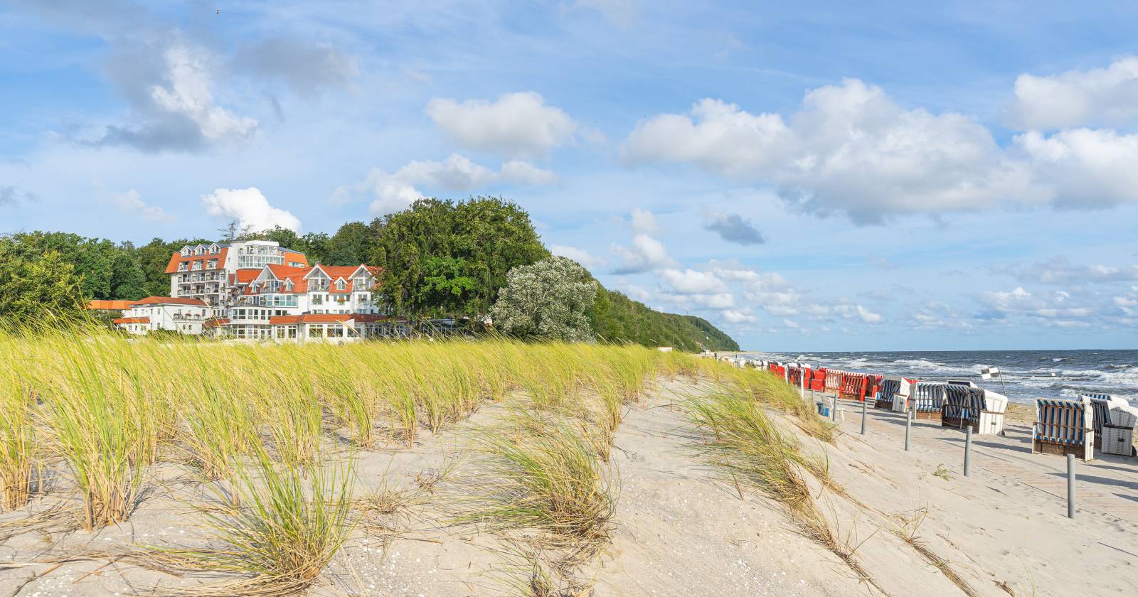 Gräser und Strandkörbe am Ostseestrand mit Blick auf das Strandhotel Seerose