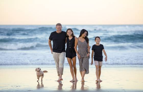 Familie mit Hund am Strand bei Sonnenuntergang